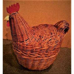 a wicker chicken sitting in a basket on top of a table next to a wall