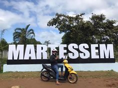 a man on a motor scooter in front of a sign that says martessm