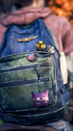 a green backpack with patches and buttons on the front, sitting next to a woman's back