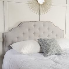 a white bed topped with pillows and a light fixture over it's headboard