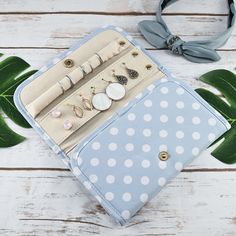 a blue and white polka dot purse with earring holders on it next to a green leaf