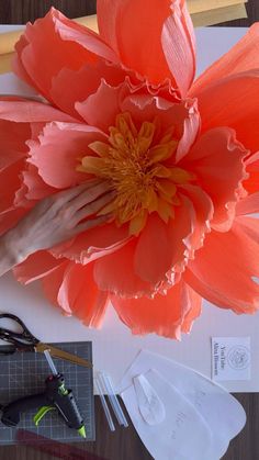 a large orange flower sitting on top of a table next to scissors and other crafting supplies