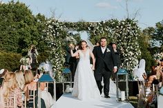 a bride and groom walking down the aisle after their wedding ceremony at an outdoor venue