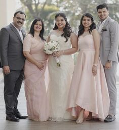 a group of people standing next to each other in formal wear posing for a photo