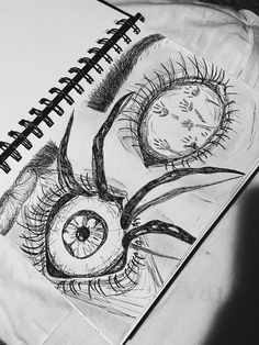 a drawing of an eyeball with long eyelashes on top of a sheet of paper