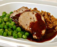 a white plate topped with meat, peas and rice