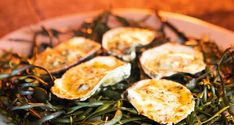 an assortment of seaweed and oysters in a bowl on a wooden table top