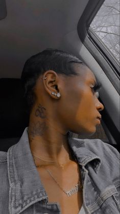 a woman sitting in the back seat of a car with tattoos on her face and neck