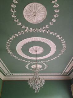 a chandelier hanging from the ceiling in a room with green walls and white trim