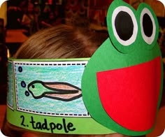 a young boy wearing a paper crown with a frog on it's head and the words 1 tadpole