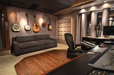 a recording studio with guitars hanging on the wall and couches in front of it