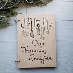 a wooden plaque with the words our family recipes on it next to some christmas decorations