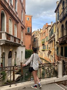 a woman standing on a bridge looking at buildings