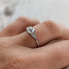 a woman's hand with a diamond ring on top of her finger, showing the center stone