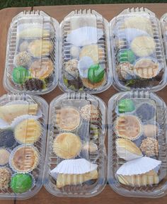 six plastic containers filled with food on top of a wooden table next to green grass