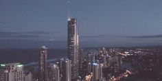 an aerial view of a city at night with skyscrapers lit up and the ocean in the background