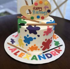 a birthday cake decorated with an artist's palette, paintbrush and acrylic letters