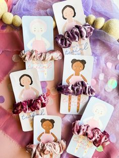 some little cards with pictures on them and hair clips in the shape of dolls sitting next to each other