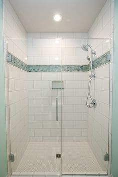 a walk in shower sitting next to a white tiled wall and floor with glass doors