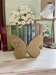 a butterfly bookend sitting on top of a table next to some books and a lamp