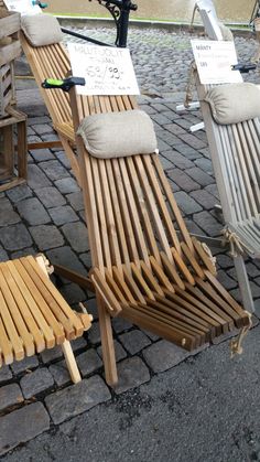 two wooden lounge chairs sitting next to each other on a cobblestone street with bicycles parked nearby