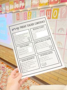 a person holding up a play parent teacher conference poster in front of a classroom wall