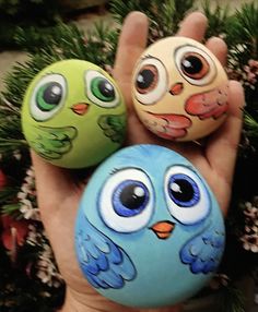 three painted rocks with eyes on them in the palm of someone's hand