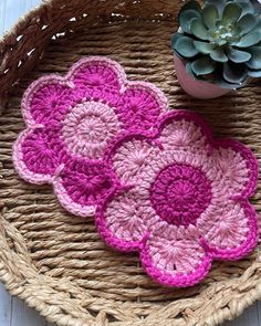 three crocheted flower coasters sitting on top of a wicker basket