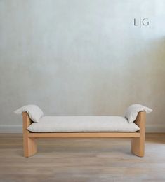 a wooden bench sitting on top of a hard wood floor next to a white wall