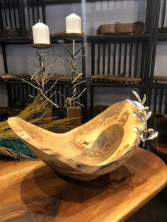 a wooden bowl sitting on top of a table next to a shelf filled with vases