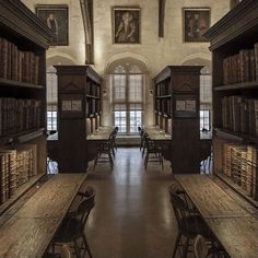 an old library with many bookshelves and tables in the center, along with paintings on the walls