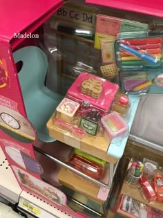 there are many toys in the box on this shelf and it is pink with white lettering