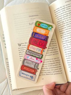 a person holding an open book with colorful books on it and the pages are lined in different colors