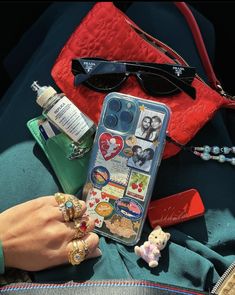 a woman's hand holding an iphone case with stickers on it and other accessories