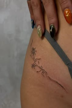 a woman's tattoo on the side of her thigh, with flowers in it