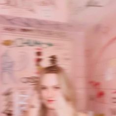 a blurry photo of a woman brushing her hair in front of a wall with writing on it