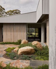 a house with large rocks in front of it and an outdoor dining area on the other side