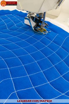 the sewing machine is on top of the blue quilted material that has been stitched together