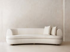 a white couch sitting on top of a hard wood floor next to a beige wall