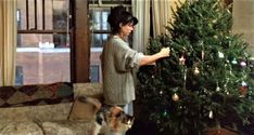 a woman decorating a christmas tree with her dog