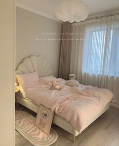 there is a bed with pink comforter and pillows on the floor next to a window