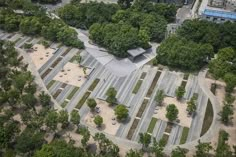 an aerial view of a parking lot in the middle of a park with benches and trees