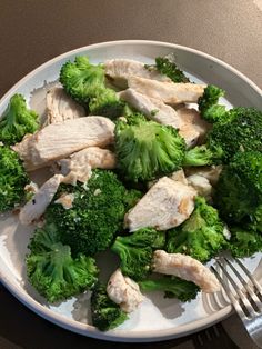 a white plate topped with broccoli and chicken next to a knife and fork