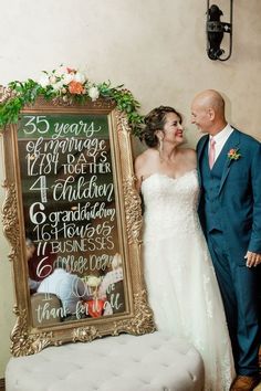 a bride and groom standing in front of a chalkboard sign for their wedding day