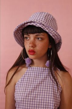 a woman with freckled hair wearing a purple and white checked dress and hat