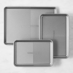 three metal trays on a marble surface