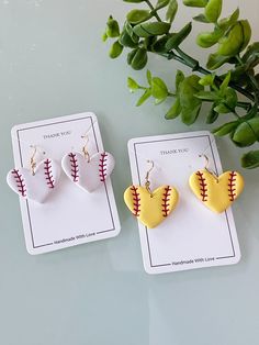 two heart shaped softball earrings sitting next to each other