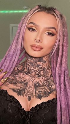 a woman with pink dread locks and tattoos on her chest is posing for the camera