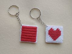 two red and white squares with a heart in the middle are shown on a keychain