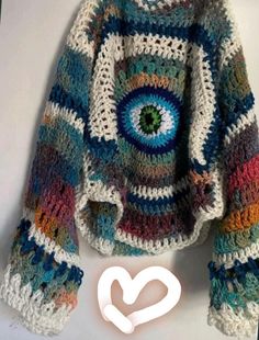 a crocheted sweater with an eye on the front, and multicolored stripes